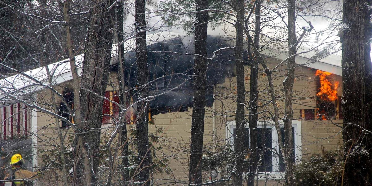 À travers bois, on devine des flammes dans la structure de la maison du chemin Pierre-Péladeau, à Sainte-Adèle, le 28 janvier