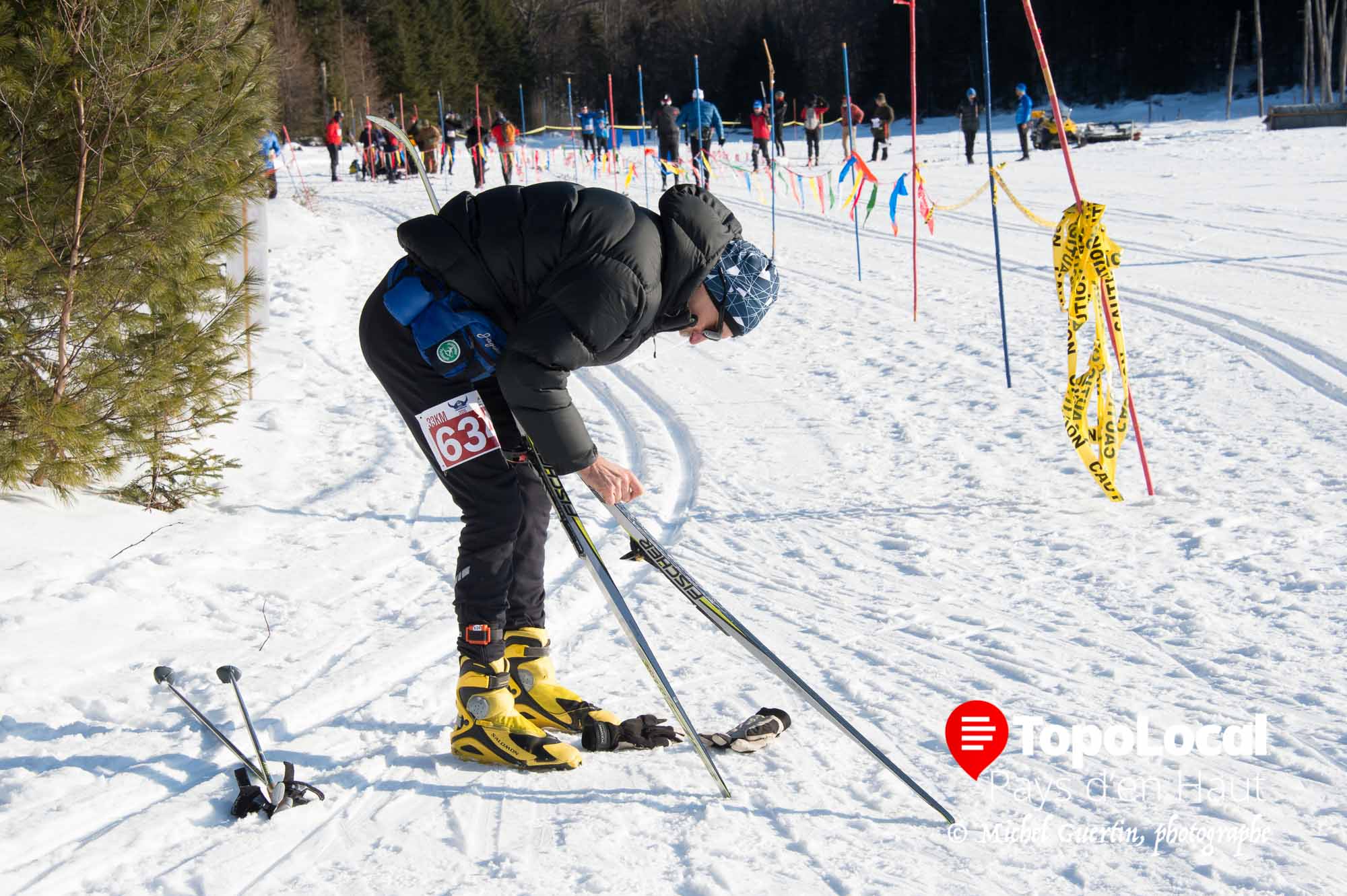 Quelques moments avant la course et après avoir fait quelques longueurs sur la piste afin de vérifier celle-ci, ce skieurs ajuste la dernière couche de cire sur ses skis