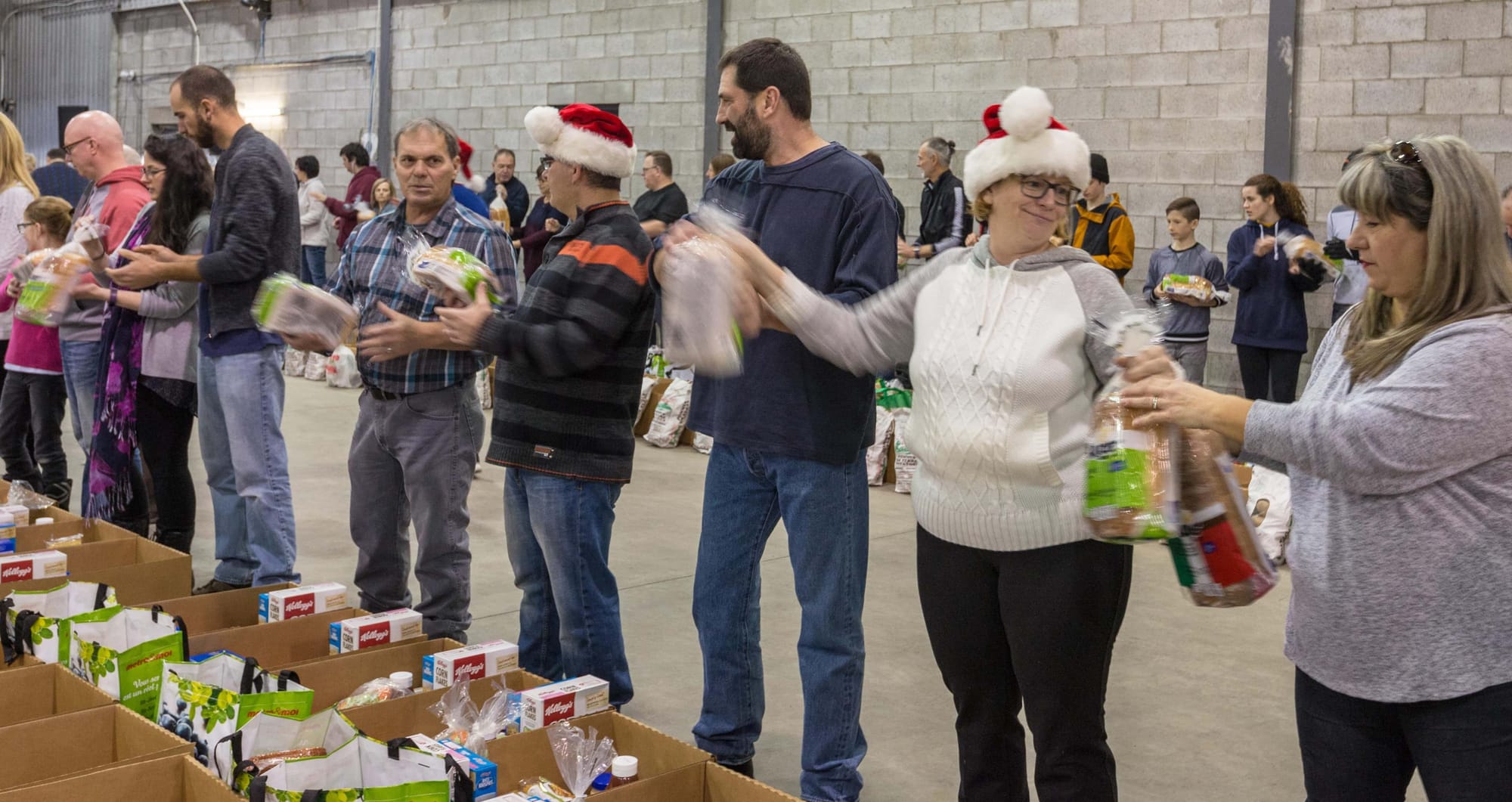 Les bénévoles chantent, jasent, dansent et s'amusent ferme au son de la musique de Noël, tout en remplissant des centaines de paniers de Noël qui seront distribués aux personnes dans le besoin.